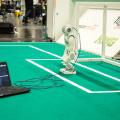 A robot connected to a computer on a soccer field.