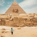 A person walking near the Sphynx and the Pyramids of Egypt.