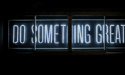 A neon sign displaying “Do Something Great”