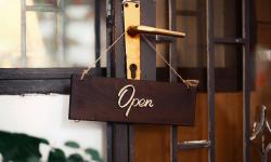 An “open” sign hanging on a wood door