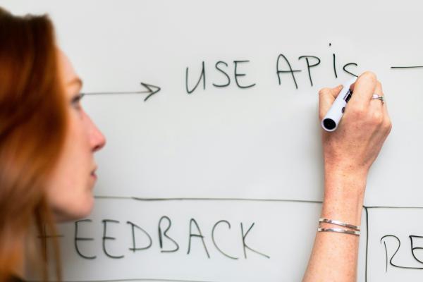 A woman writing ‘Use APIS’ on a white board.
