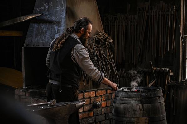 A skilled blacksmith working in his rustic workshop, crafting metal with traditional tools.