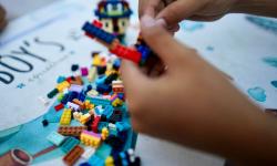 Children’s hands play with colorful toy blocks on a table inside a room in East Java, Indonesia.