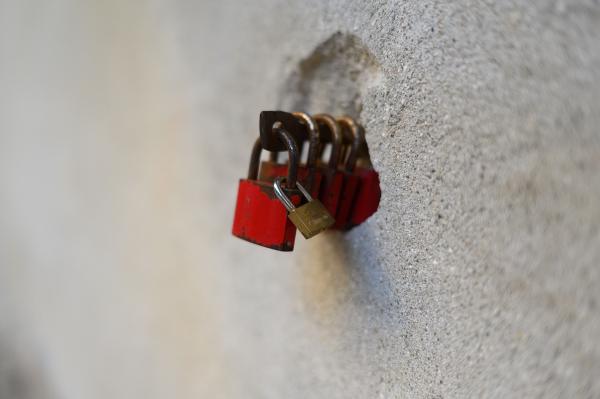 A series of red padlocks attached to a stone wall